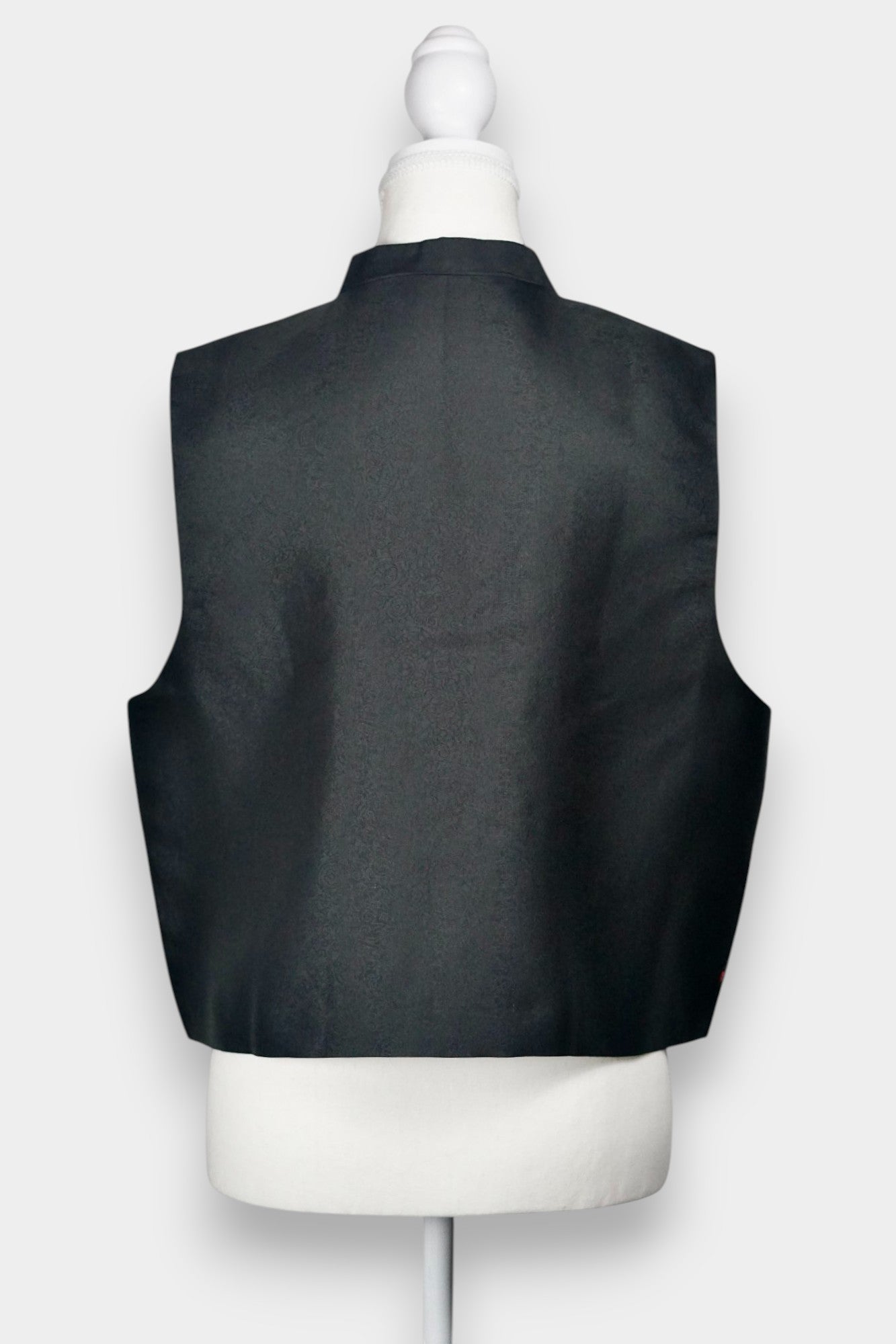 Women's black Song Brocade vest with a mandarin collar, frog buttons, and colorful woven traditional patterns on the hem.