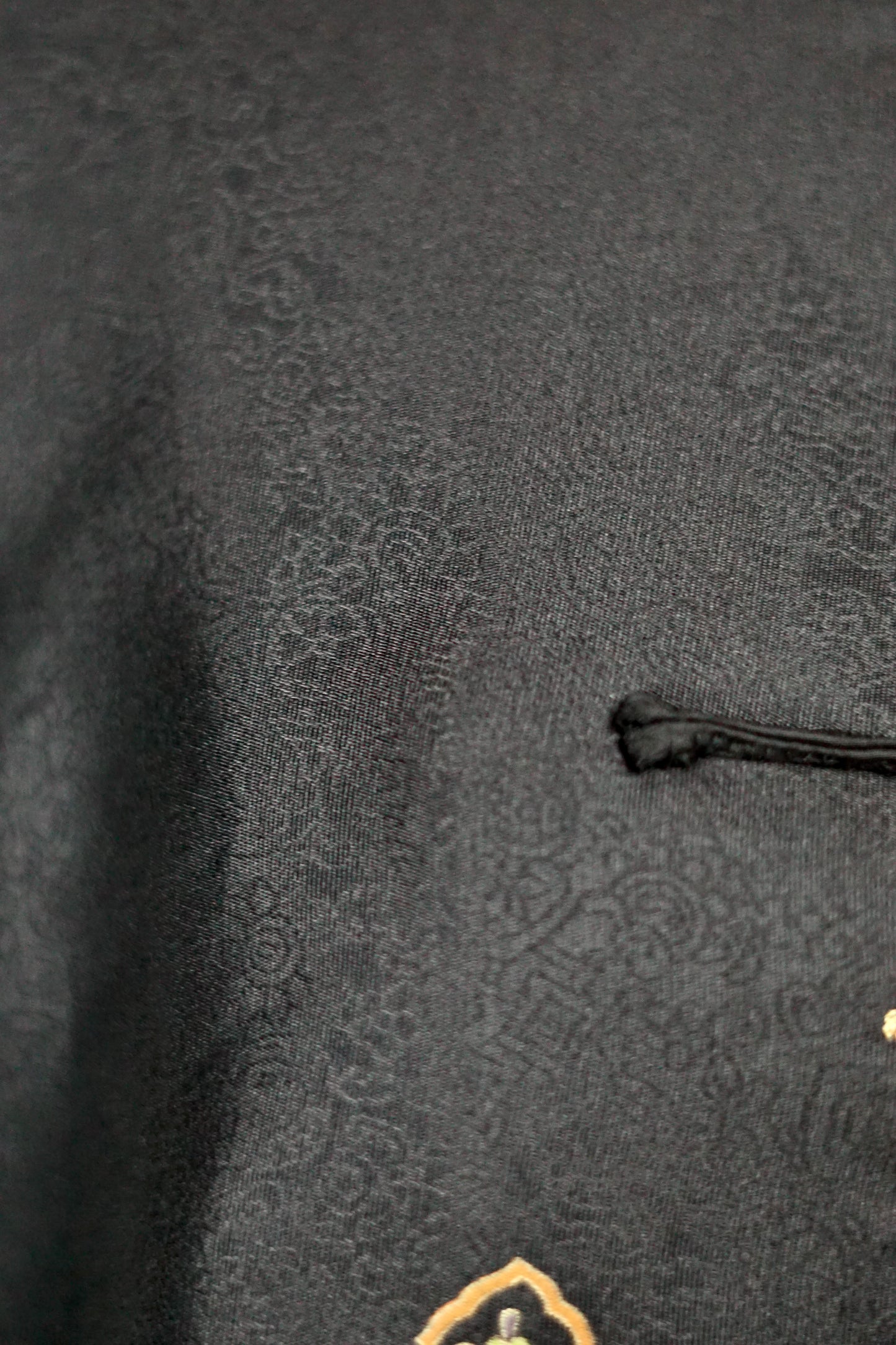 Women's black Song Brocade vest with a mandarin collar, frog buttons, and colorful woven traditional patterns on the hem.