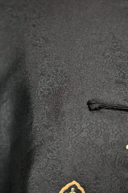 Women's black Song Brocade vest with a mandarin collar, frog buttons, and colorful woven traditional patterns on the hem.