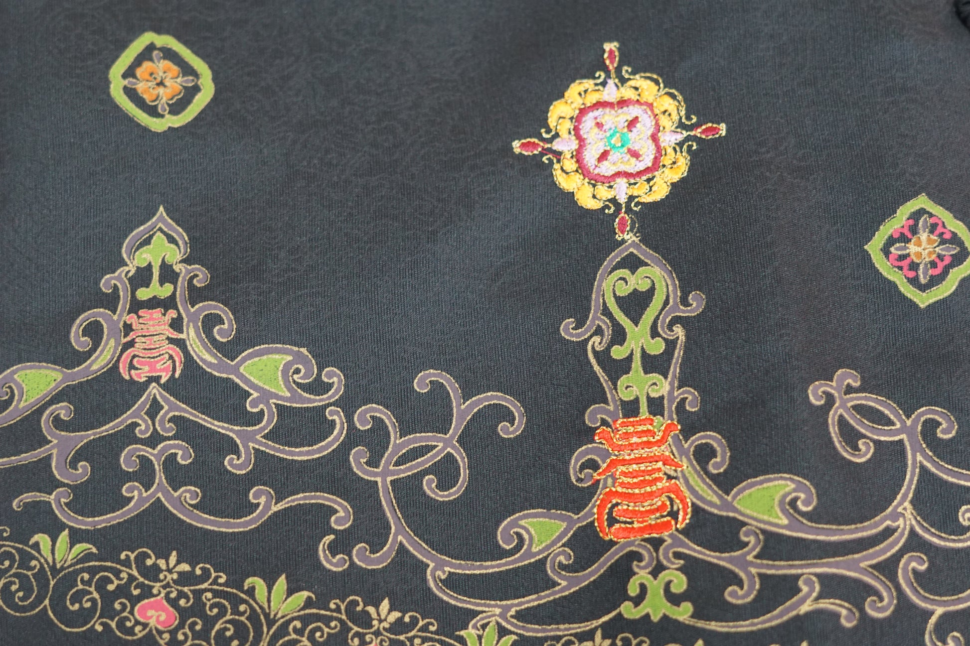 Women's black Song Brocade vest with a mandarin collar, frog buttons, and colorful woven traditional patterns on the hem.