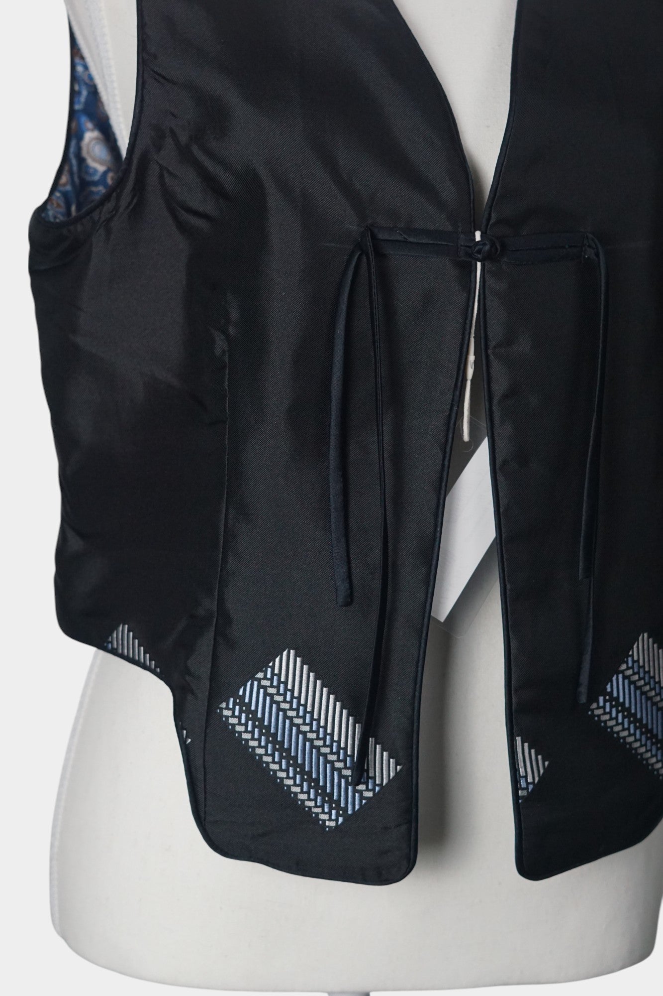 Black Song Brocade vest with V-neck, front tie closure, and white geometric hem details