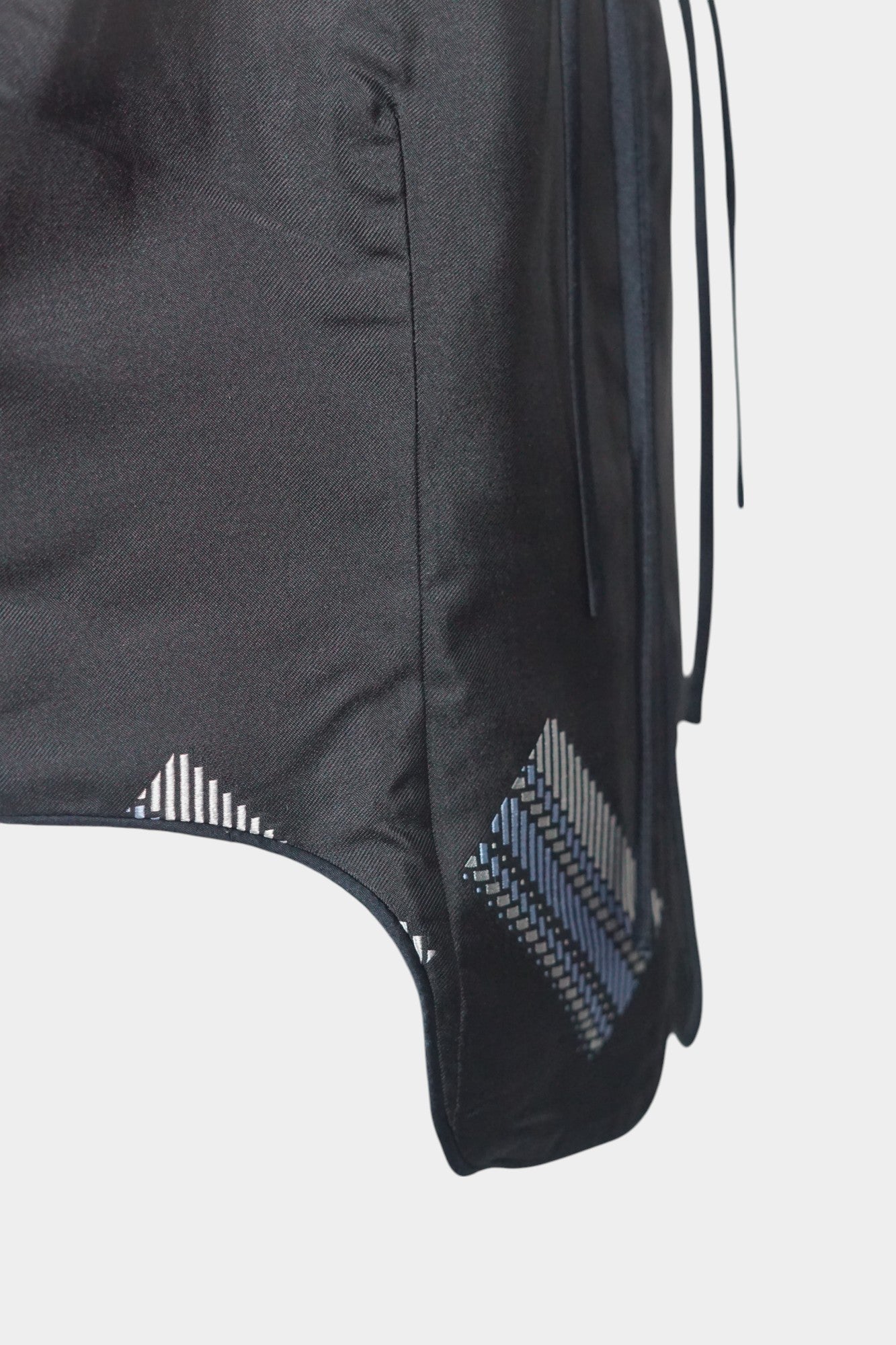 Black Song Brocade vest with V-neck, front tie closure, and white geometric hem details
