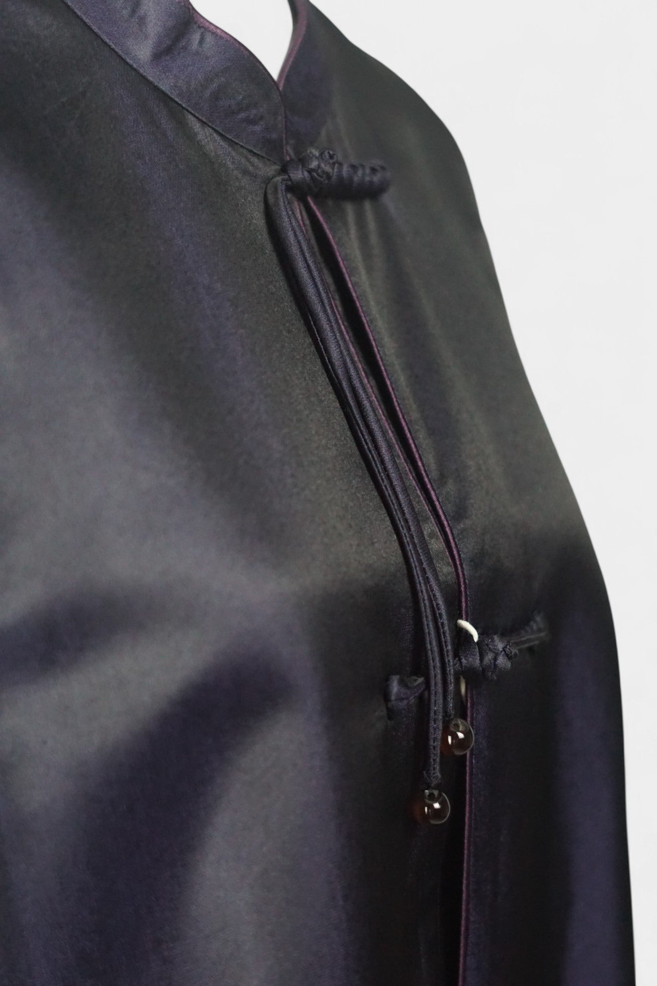 Women's dark purple Song Brocade vest with a mandarin collar, purple piping, and traditional frog buttons with tassels.