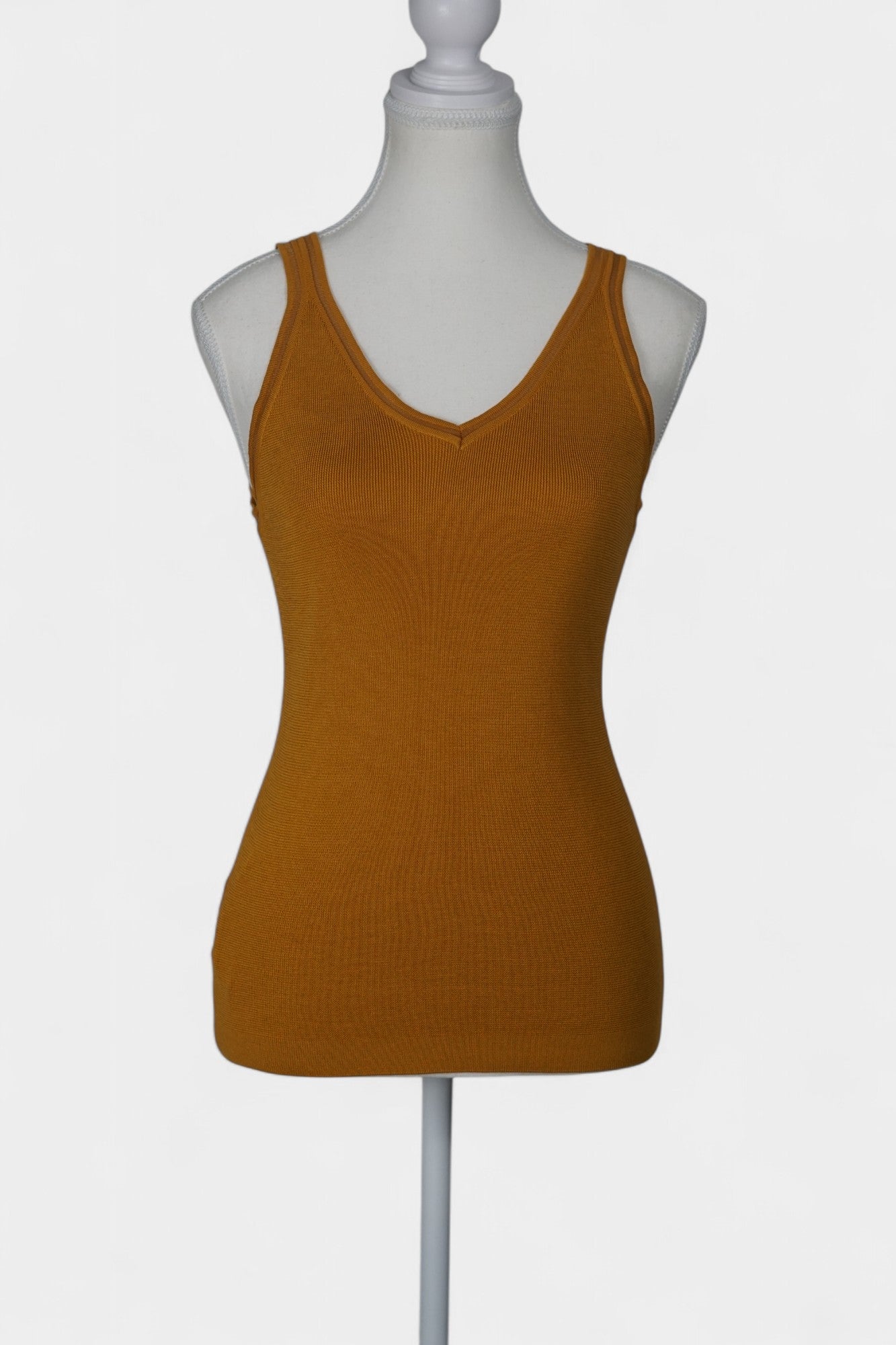 Rear view of a mustard-colored knit tank top on a white mannequin, featuring wide straps and a clean V-shaped neckline at the back.