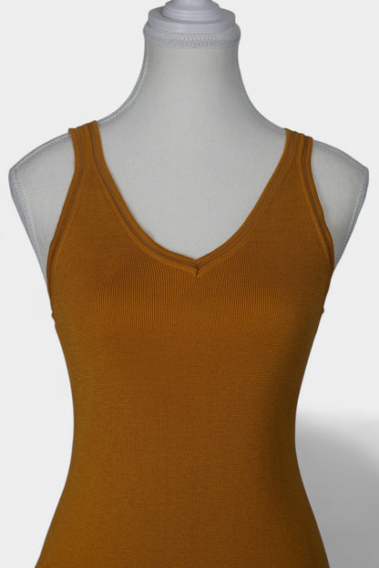 Rear view of a mustard-colored knit tank top on a white mannequin, featuring wide straps and a clean V-shaped neckline at the back.