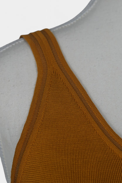 Rear view of a mustard-colored knit tank top on a white mannequin, featuring wide straps and a clean V-shaped neckline at the back.